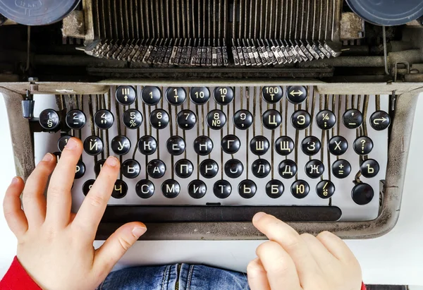 Cute little girl typing on vintage typewriter keyboard — Stock Photo, Image