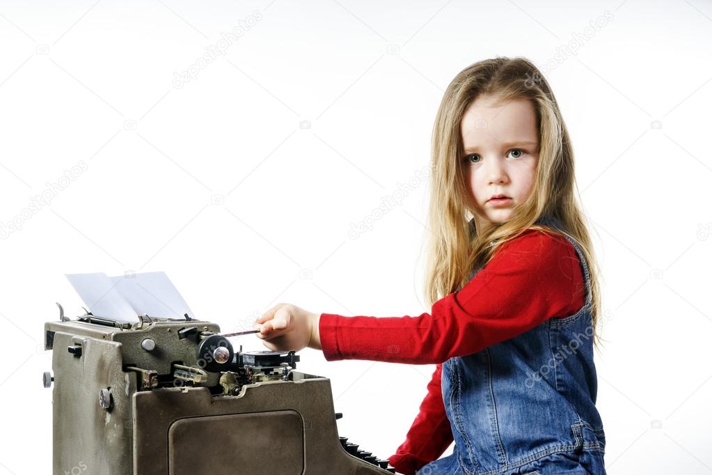 Cute little girl typing on vintage typewriter keyboard