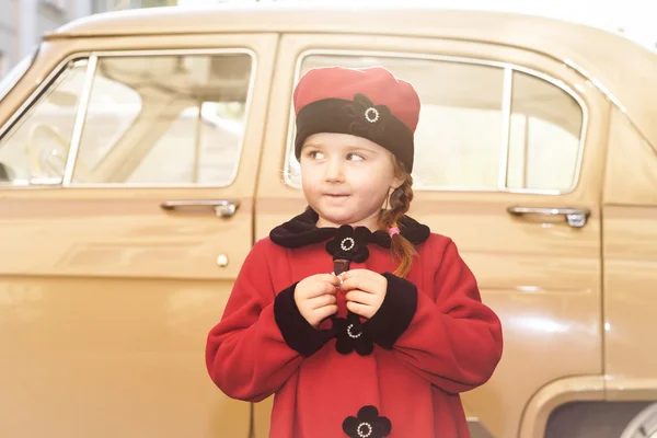 Menina bonito vestido com casaco retro posando perto de carro oldtimer — Fotografia de Stock