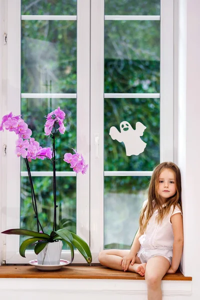 Cute little girl with flower sitting on windowsill of new pvc wi — Stock Photo, Image