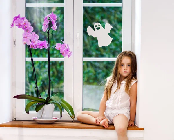 Sevimli küçük kız yeni PVC pencere kenarında oturan çiçek ile kablosuz — Stok fotoğraf