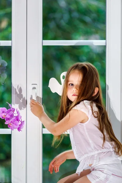 Linda niña con flor sentada en el alféizar de la ventana de pvc nuevo wi —  Fotos de Stock