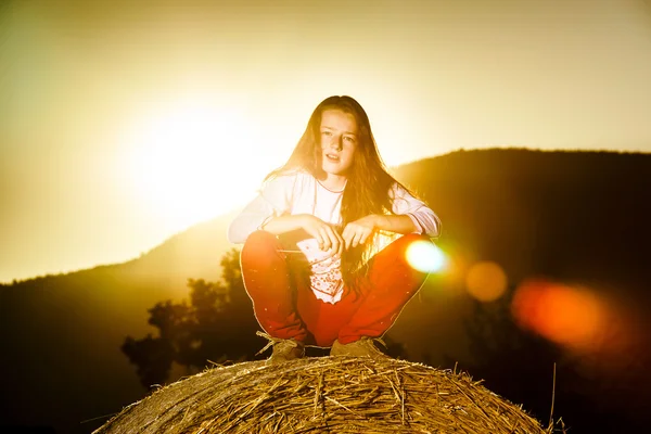 Menina adolescente posando à noite no palheiro, cores do pôr do sol — Fotografia de Stock
