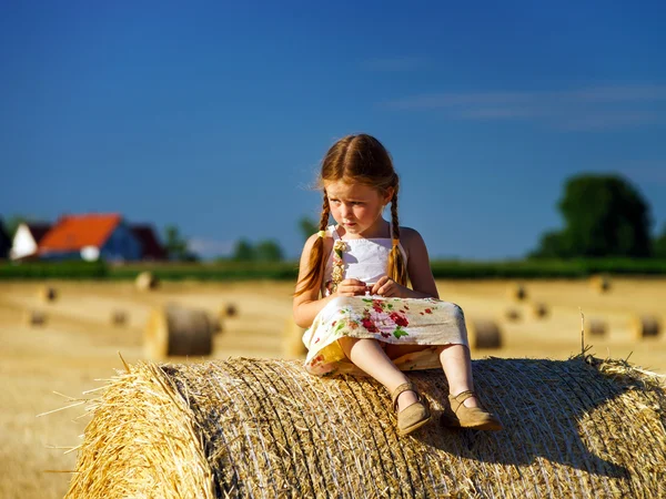 Petite fille mignonne drôle posant sur la meule de foin dans le champ d'été — Photo