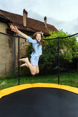 Cute teenage girl jumping on trampoline clipart