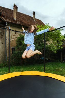 Cute teenage girl jumping on trampoline clipart