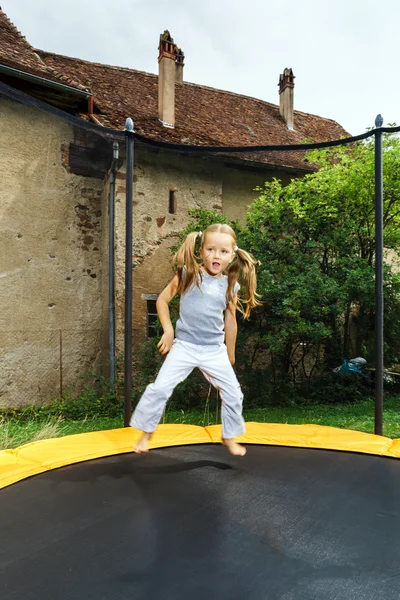 Linda niña en edad preescolar saltando en trampolín —  Fotos de Stock