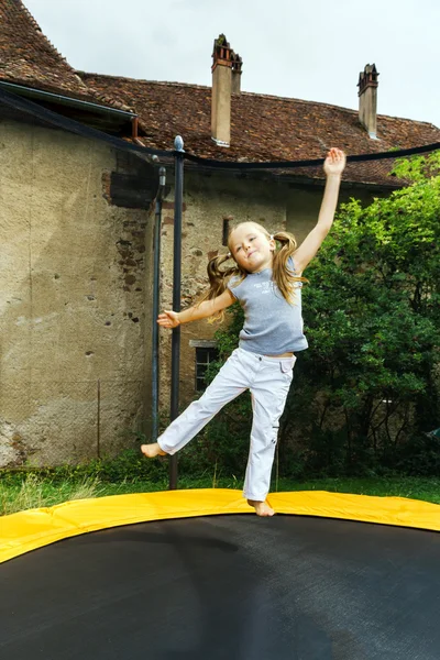 Linda niña en edad preescolar saltando en trampolín —  Fotos de Stock