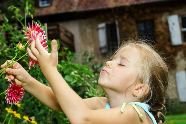 Söta förskolebarn flicka stående med blommor — Stockfoto