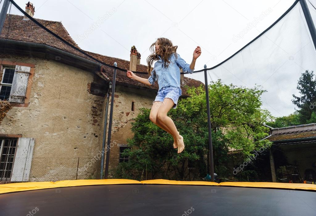 Cute teenage girl jumping on trampoline