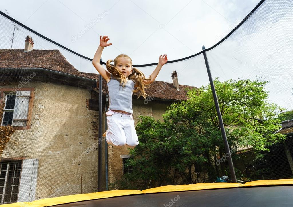 Cute preschooler girl jumping on trampoline