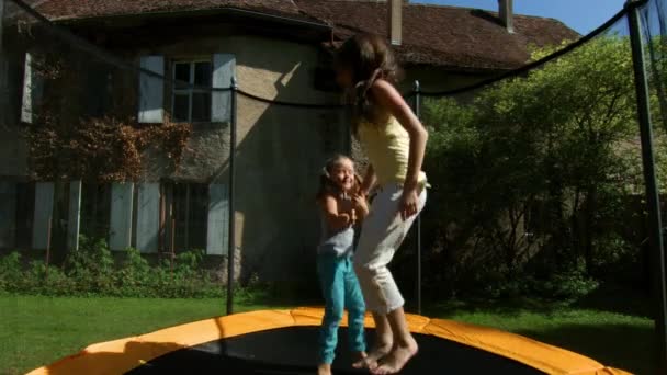 Dvě sestry, skákání na trampolíně v zahradě — Stock video