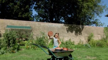 Sevimli küçük kız el-barrow arka bahçesinde, yaz günü tesisi