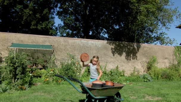 Cute little girl riding hand-barrow in the backyard, summer day — Stock Video