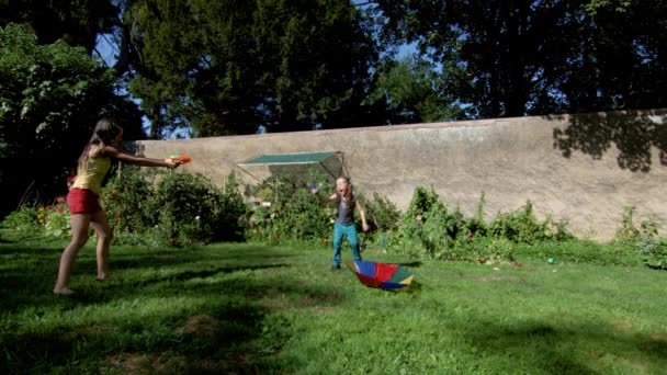 Due sorelle felici che giocano con l'irrigazione del giardino nel cortile — Video Stock