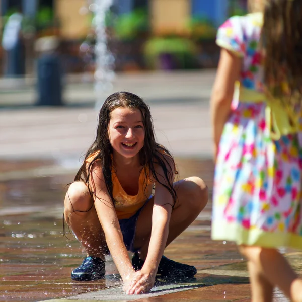 Two sisters playing with fountain splash — Stock Photo, Image