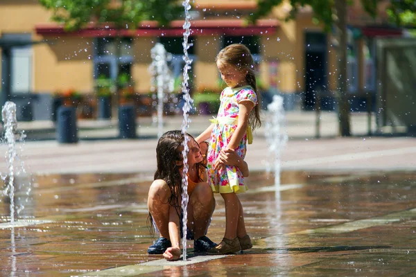 Dos hermanas jugando con salpicaduras de fuente — Foto de Stock