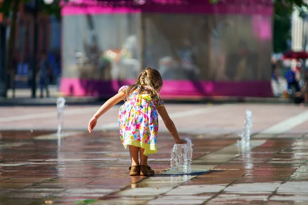 Schattig klein meisje spelen met fontein splash — Stockfoto