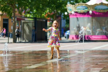 Çeşme sıçrama ile oynayan sevimli küçük kız