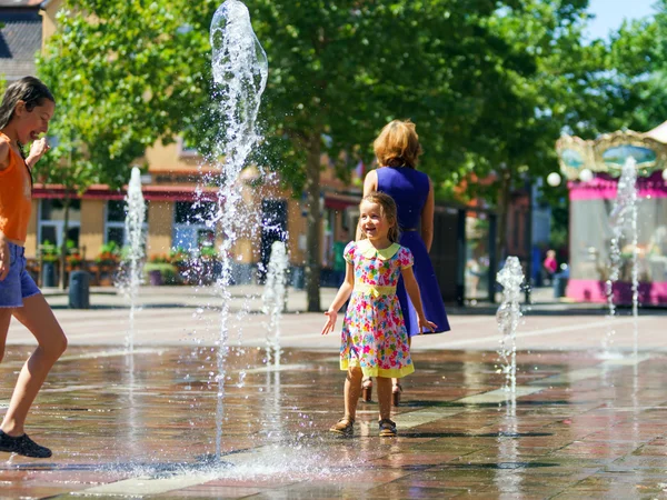 Two sisters playing with fountain splash — Stock Photo, Image