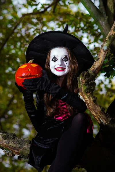 Ragazza adolescente vestita in costume da strega seduta sull'albero — Foto Stock