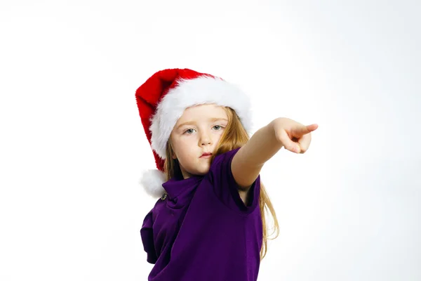 Cute little girl in santa red hat showing by hand — Zdjęcie stockowe