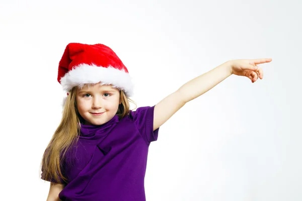 Cute little girl in santa red hat showing by hand — Stockfoto