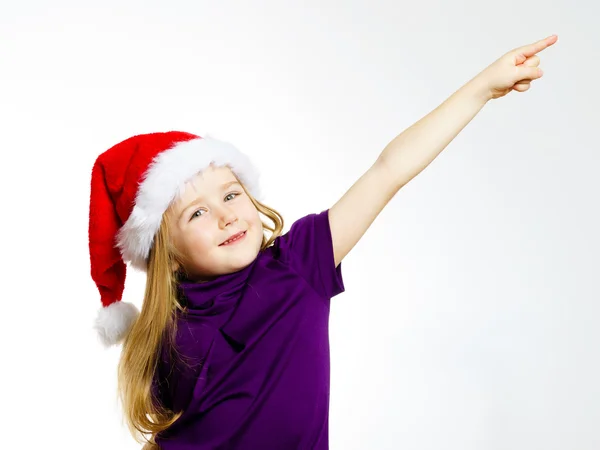 Cute little girl in santa red hat showing by hand — Zdjęcie stockowe