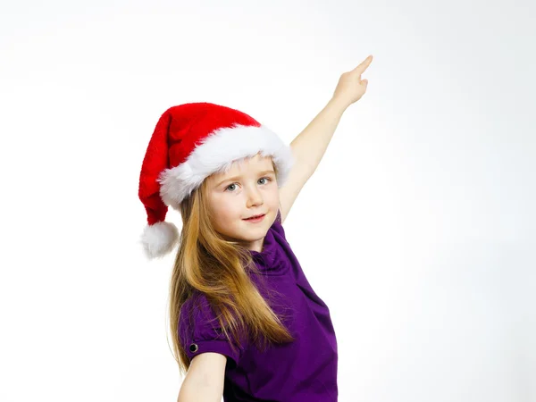 Cute little girl in santa red hat showing by hand — Stockfoto