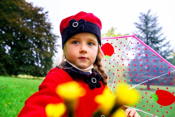 Menina bonito vestido com casaco vermelho e chapéu na grama verde fiel — Fotografia de Stock