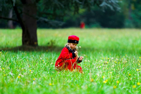 Μικρό κορίτσι ντυμένοι με κόκκινο χρώμα στο πεδίο πράσινο γρασίδι — Φωτογραφία Αρχείου