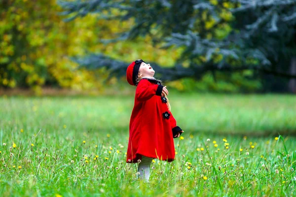 Petite fille habillée en rouge sur champ d'herbe verte — Photo