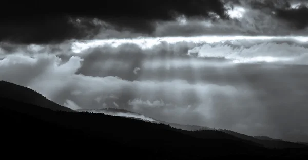 Beautiful sun rays through the clouds over mountains — Stock Photo, Image