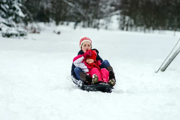 Two sisters riding by sleds winter day — Stock Photo, Image