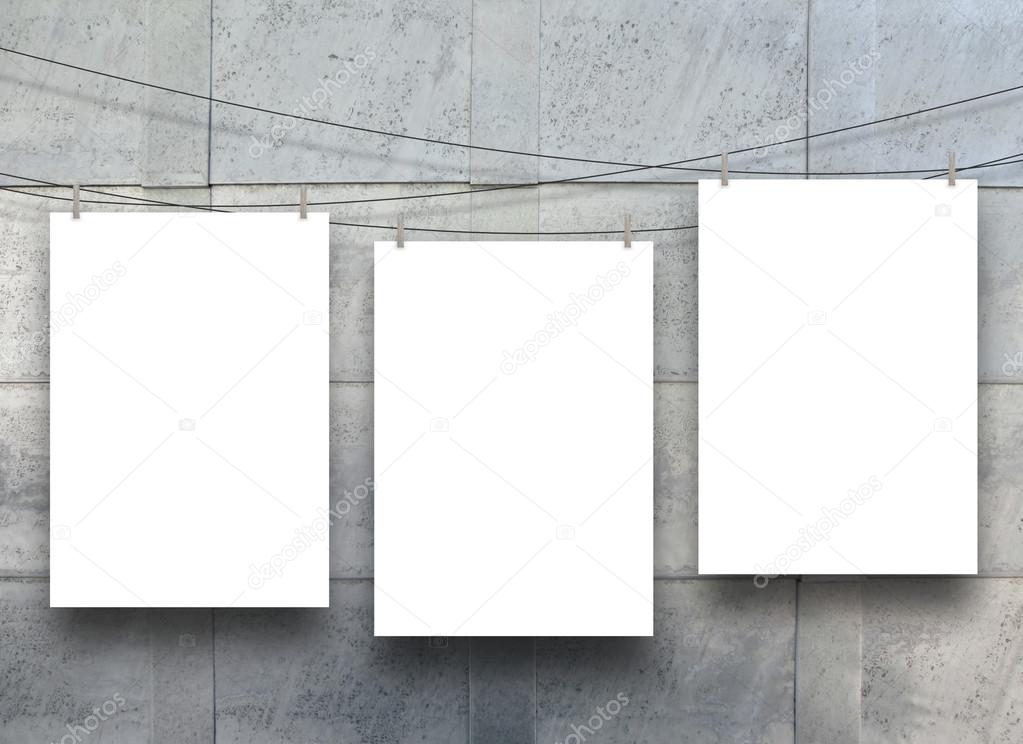 Three empty frames hanged by pegs on blue metal sheet