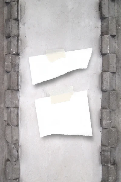 Twee geripte stukjes papier met tape op ingerichte betonnen wand — Stockfoto