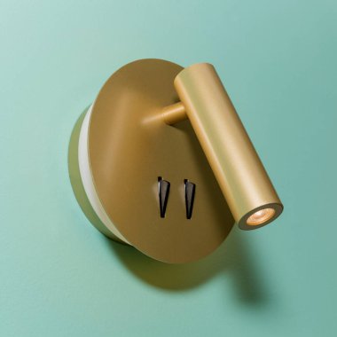 Turkuaz renkli duvarda parlak, modern bir metal lamba. Boş alan.