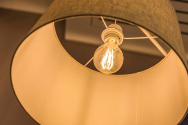 Tekstil tavan tepesinden yapılmış parlak bir lamba. Sıcak, sarı, parlak bir ışık yanıyor. İç dekorasyon kavramı. Kapalı.