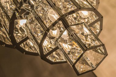 Kristal tavan abajurundaki lüks avizeye yakın çekim. Modern bir iç mekanda klasik tarz. İçeri gir. Sıcak ışık.