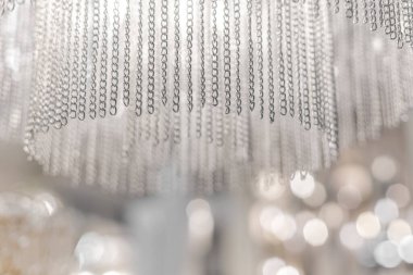 Zincirlerden yapılmış pahalı bir avizeye yakın plan. Modern bir iç mekanda eşsiz bir stil. İçeride. Soğuk ışık.