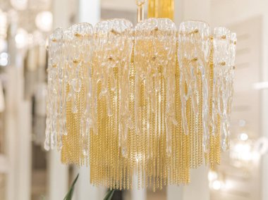 Zincirlerden yapılmış sarı, lüks, pahalı bir avizeye yakın plan. Modern bir iç mekanda eşsiz bir stil. İçeri gir. Soğuk ışık.