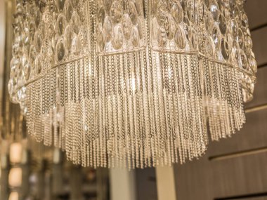 Zincirlerden yapılmış pahalı bir avizeye yakın plan. Modern bir iç mekanda eşsiz bir stil. İçeride. Sıcak ışık.