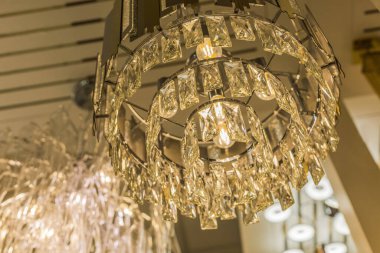 Şeffaf bir kristal tavan abajurundan parlak, pahalı bir avize. Modern bir iç mekanda klasik tarz. İçeri gir. Sıcak ışık.