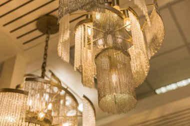 Zincirden yapılmış pahalı bir avizenin kapağını kapatın. Modern bir iç mekanda eşsiz bir stil. İçeri gir. Sıcak ışık.