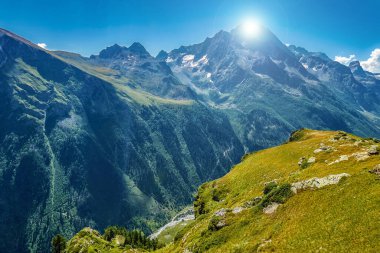 Parlak güneş dağın tepesinin arkasında saklanır. Tepeden manzara. Bulutsuz gökyüzü ve doğal uzay. İş düşüncesi, iyi bir fikir veya mesaj..