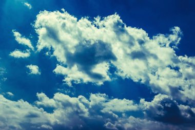 Alacakaranlık ışığında kabarık beyaz güneş bulutları koyu mavi gökyüzüne doğru süzülür. İlahi görüş. Rüya, sihir, astroloji, gizem.