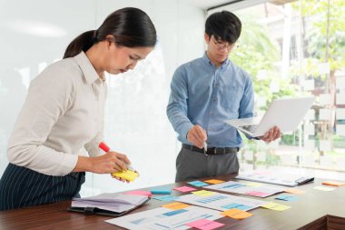 Beyin fırtınası yapan yaratıcı iş adamları grubu, iş konferansı odasında plan geliştirmek için konsept seçme konusunda fikir paylaşmak için yapışkan notlar seçiyor.