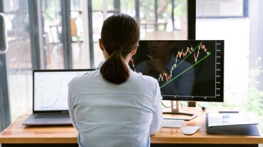 Grafiklerle çalışan borsa simsarı, modern ticaret ofisindeki monitörde şemalar var..