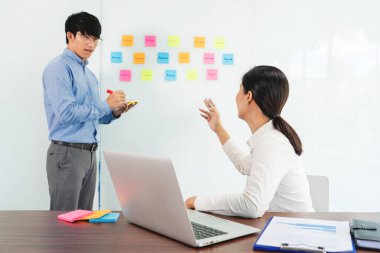 İşletme müdürü kendi takımı için fikir sunuyor ve cam pencere üzerine birçok not yapıştırıyor. İş görüşmeleri, yaratıcı ofis, planlama ve yönetim kavramında başarılı olmak için.