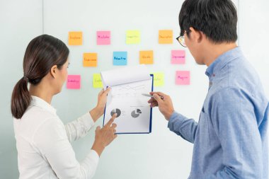 İşletme müdürü kendi takımı için fikir sunuyor ve cam pencere üzerine birçok not yapıştırıyor. İş görüşmeleri, yaratıcı ofis, planlama ve yönetim kavramında başarılı olmak için.